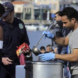 Lesvos island, volunteers on the port, offering meals to migrant newcomers by the aid of the Greek Coastguard